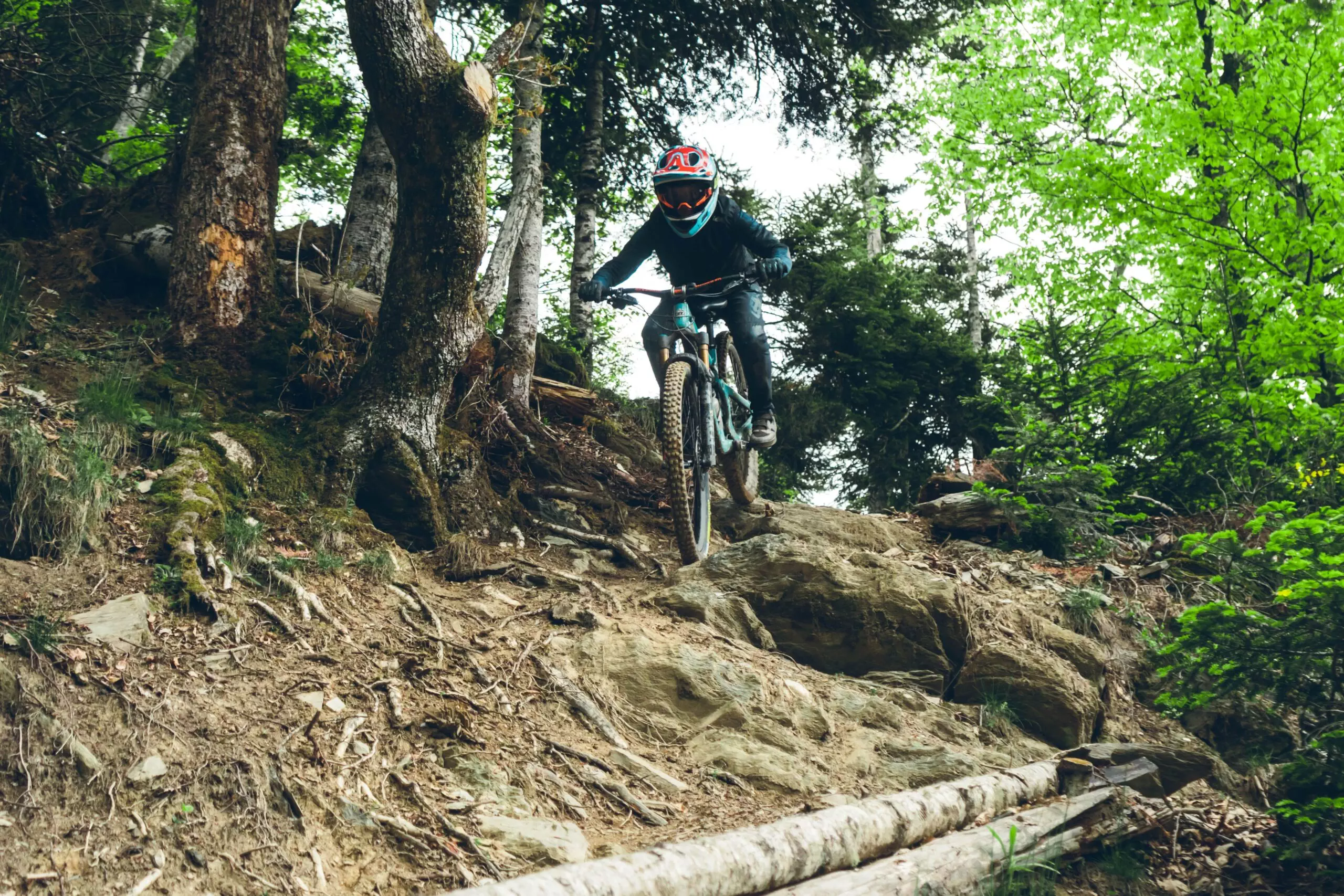 Vététiste équipé descendant un sentier technique en forêt à Loudenvielle dans les Pyrénées, sur un parcours VTT enduro.